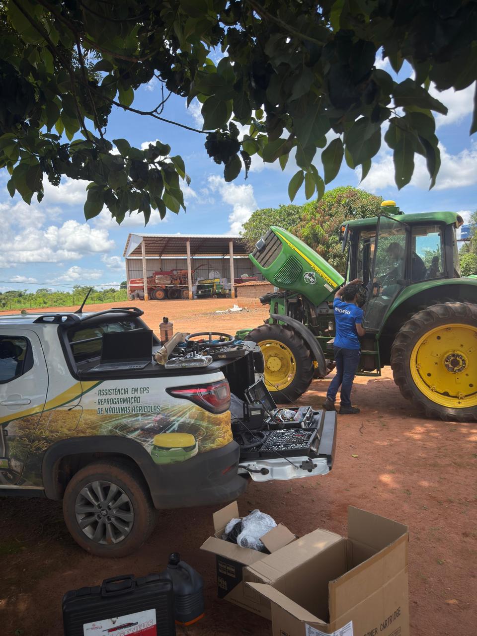 Técnicos da Agro BS reprogramando um trator John Deere, com a caminhonete e o notebook ao lado